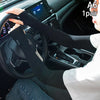A pair of black summer ice silk anti-sunburn arm sleeves being worn on a steering wheel.
