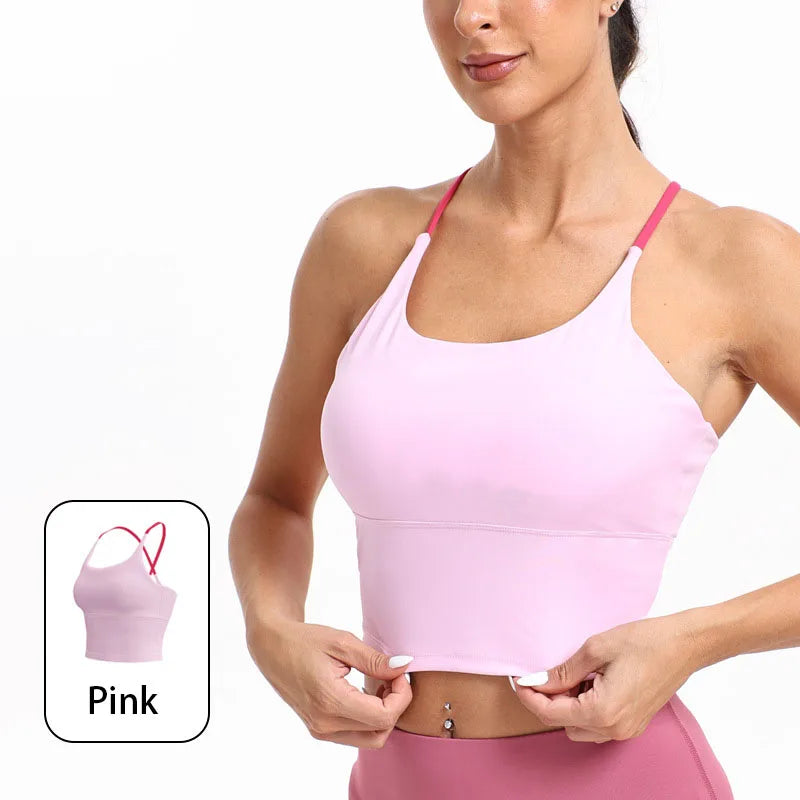 A woman models a pink summer strappy yoga sports bra with built-in padding.