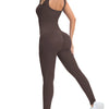 A model wearing a dark brown ribbed nylon bodycon jumpsuit with a sleeveless back and white sneakers.