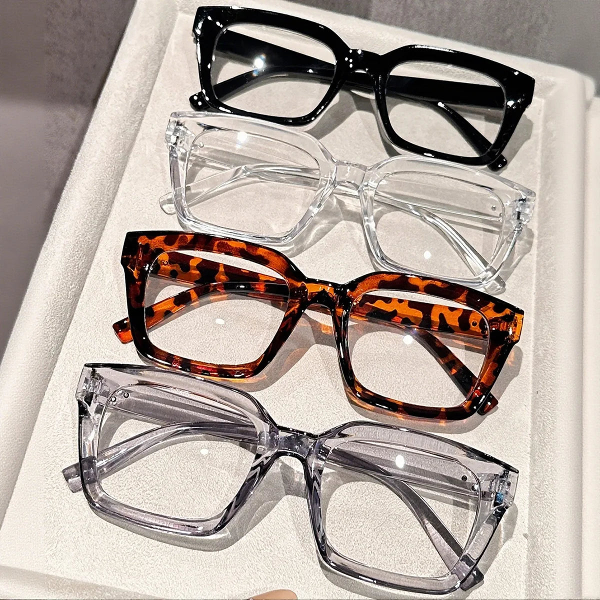 A display of five pairs of square anti-blue light eyewear in various frames and colors.