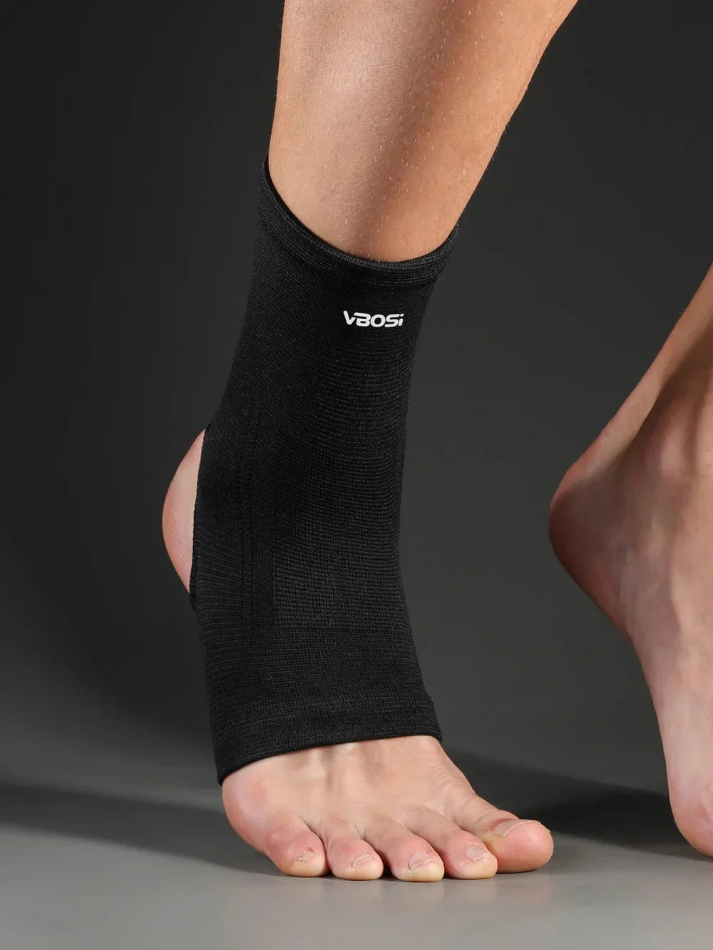 A black Vbasi ankle support brace is worn on a person's lower leg.