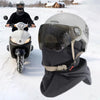 A person wearing a black balaclava and helmet is riding a motorcycle in the snow.