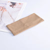 A beige ribbed knitted headband lying next to a magazine featuring a woman's hand and arm.