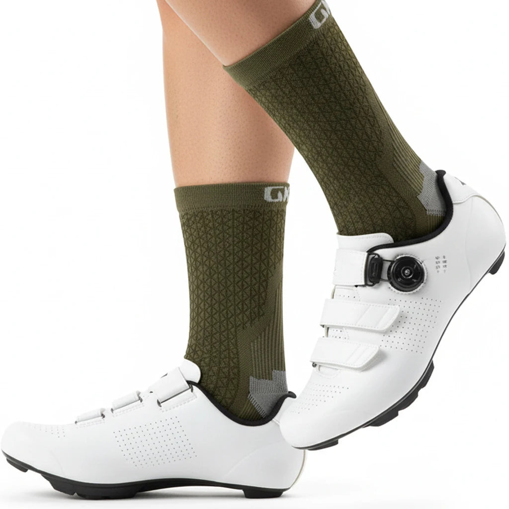A pair of white cycling shoes with olive green socks and a black strap are shown on a person's foot.
