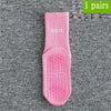 Ein Paar rosa atmungsaktiver rutschfester Yoga- und Fitnesssocken auf einer grauen strukturierten Oberfläche.