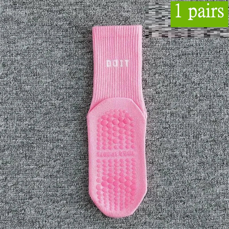 Ein Paar rosa atmungsaktiver rutschfester Yoga- und Fitnesssocken auf einer grauen strukturierten Oberfläche.