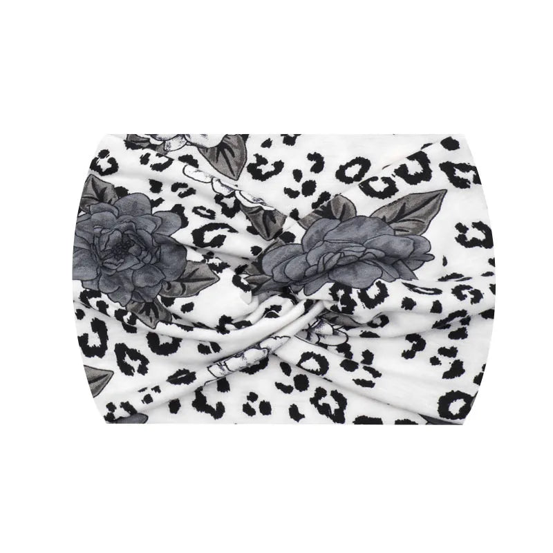 A white fabric headband with a black leopard print pattern, tied in a knot.