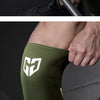 A close-up of olive green compression knee sleeves worn on a person's leg.