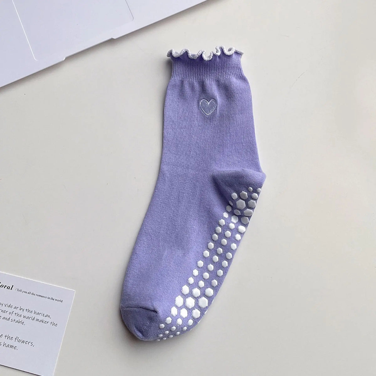 A purple yoga sock with a delicate lace trim and silver stud detailing on the toe area.
