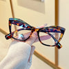 A hand holds a pair of vintage color block blue light blocking eyeglasses with brown and amber patterns.