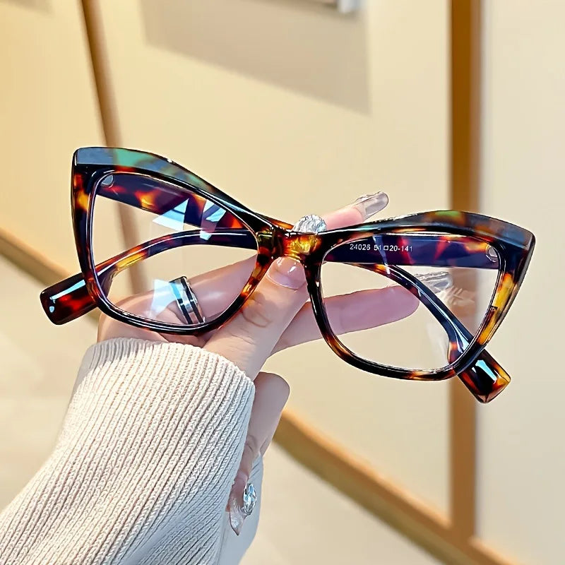 A hand holds a pair of vintage color block blue light blocking eyeglasses with brown and amber patterns.