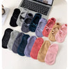 A collection of various colored and patterned crisscross strap yoga socks laid out on a white surface.