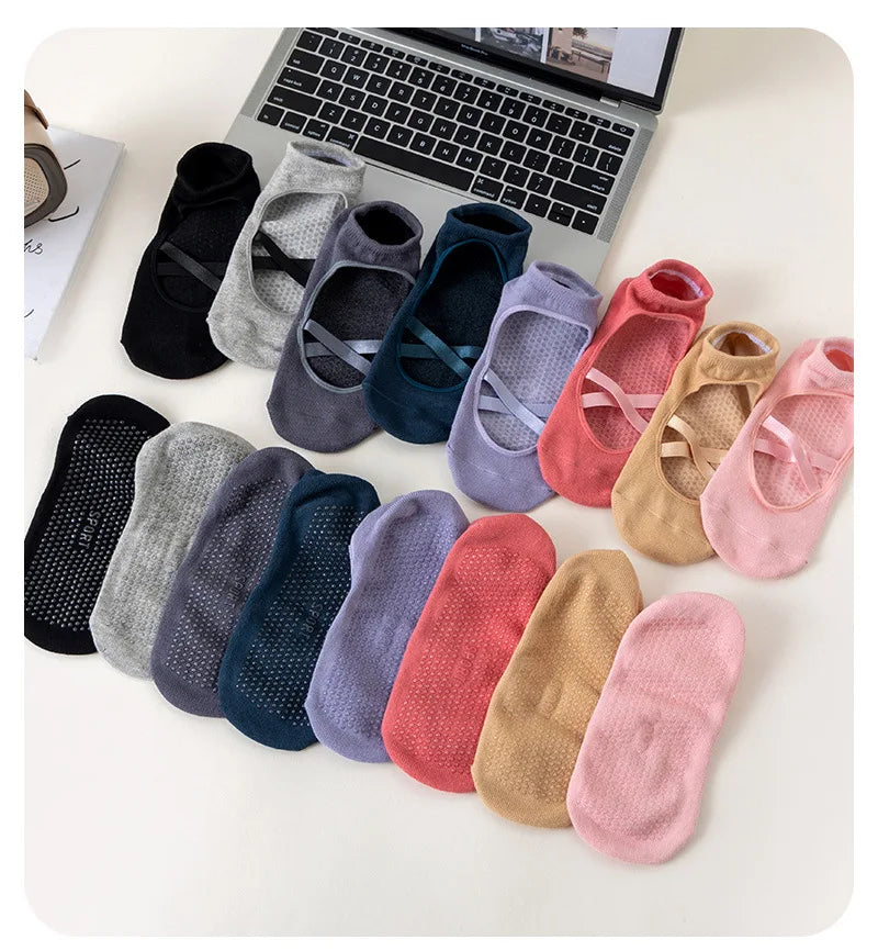 A collection of various colored and patterned crisscross strap yoga socks laid out on a white surface.
