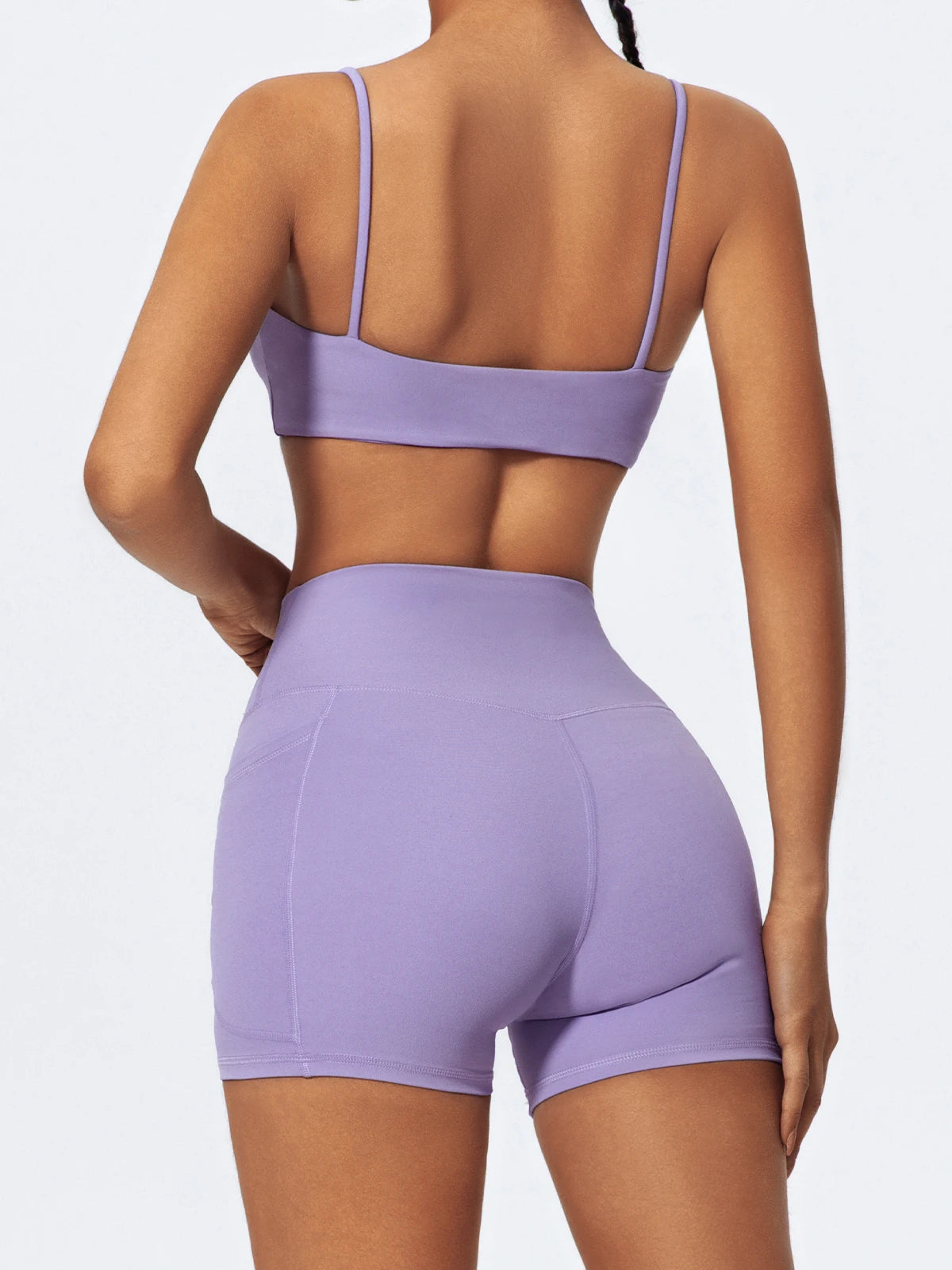 A woman wearing purple high-waist yoga shorts and a matching crop top, shown from the back.