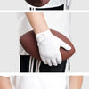 Una persona con guantes blancos sostiene un balón de rugby marrón.