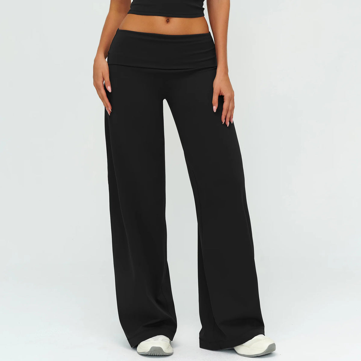 A model wearing black flared high-waist yoga and fitness pants with a black crop top.
