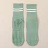 A pair of mint green non-slip yoga socks with white stripes and textured soles.