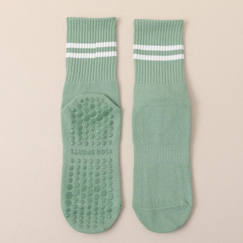 A pair of mint green non-slip yoga socks with white stripes and textured soles.