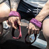 A close-up of a person's hands wearing purple gym wrist wraps while performing a strength training exercise.