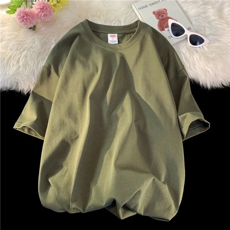 Olivgrüne, oversized Baumwoll-T-Shirt für Damen, flach auf einer weißen, flauschigen Oberfläche.