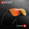 A pair of orange-tinted frameless sports sunglasses resting on a black surface next to its packaging.