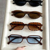 A display of four pairs of retro fashion sunglasses in various shades and styles on a white tray.
