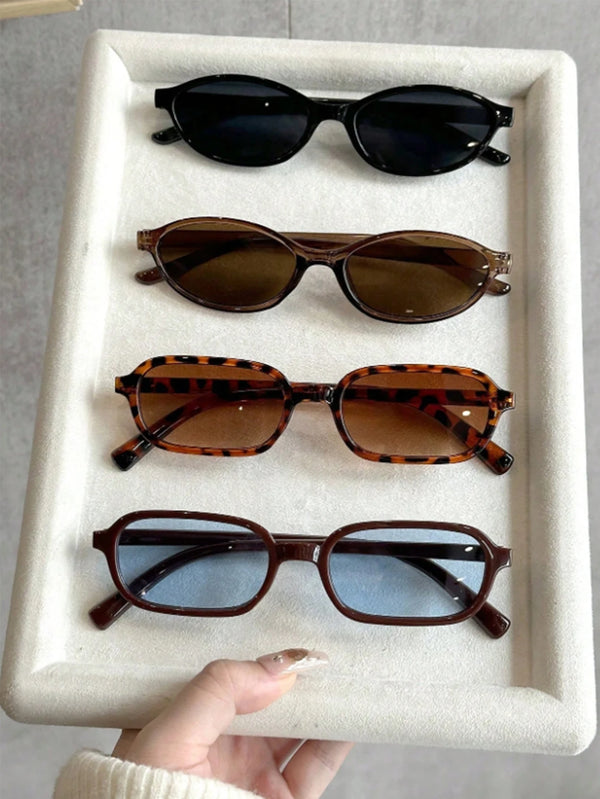 A display of four pairs of retro fashion sunglasses in various shades and styles on a white tray.