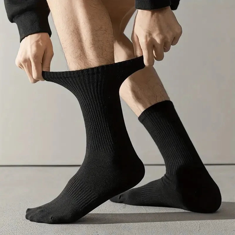 Une personne met des chaussettes de tube tricotées noires pour le confort toute saison.
