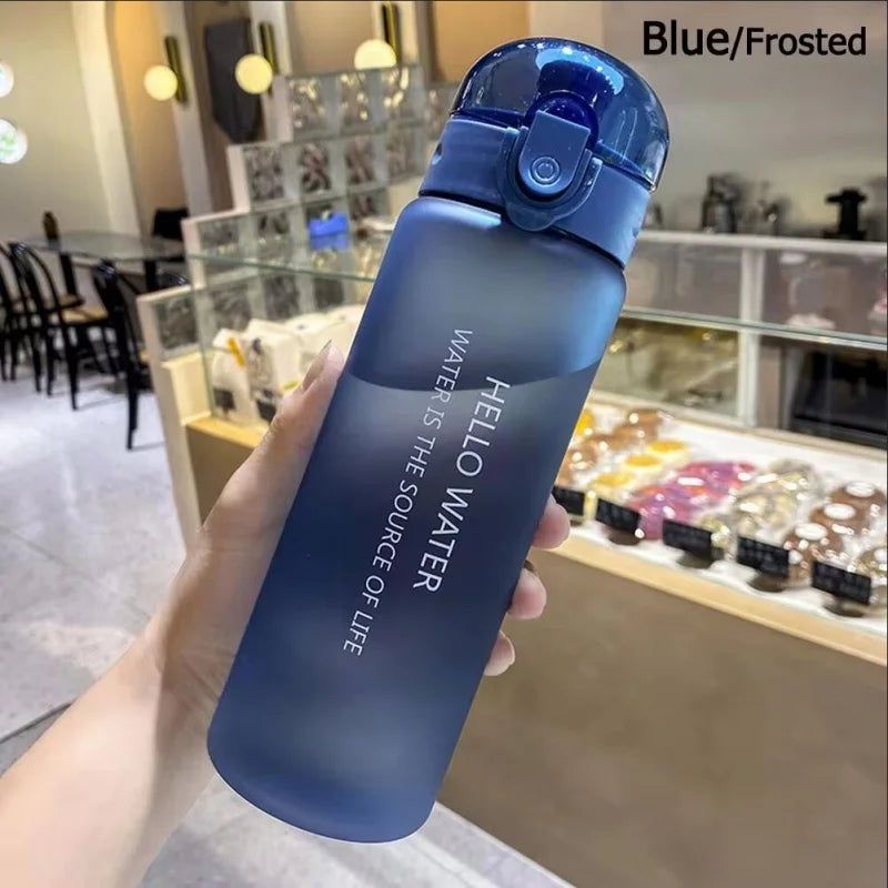Eine Hand hält eine blaue, glasierte Sportflasche mit blauem Deckel, beschriftet: Hello Water ist die Quelle des Lebens.