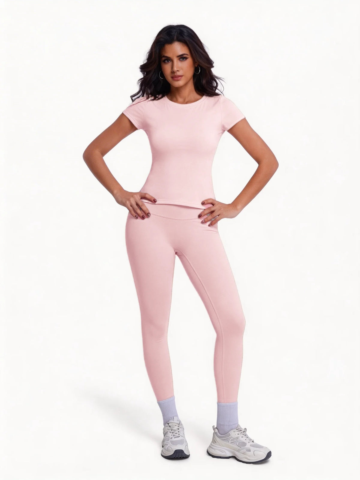 Una mujer modela un conjunto de yoga sin costuras de tiro alto en rosa claro con top de manga corta y leggings a juego.