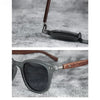 A close-up of brown wood grain polarized sunglasses resting on a gray textured surface.