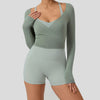 A woman wearing a sage green long sleeve top and matching high-waisted leggings for yoga or sport.
