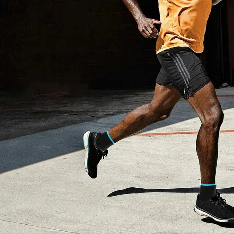 A person wearing black compression socks is running outdoors on a concrete surface.