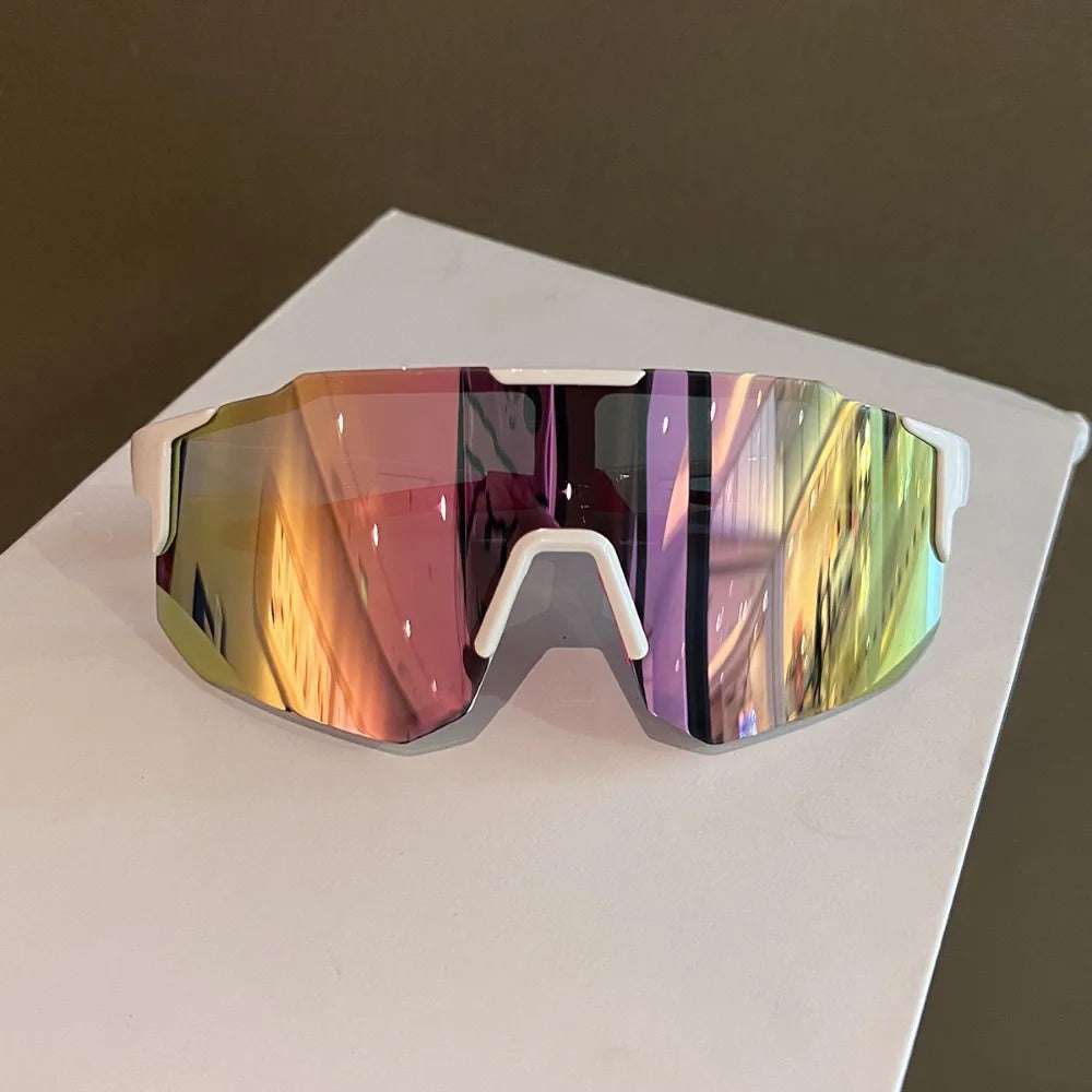 A pair of mirrored sport cycling and skiing goggles resting on a white surface.