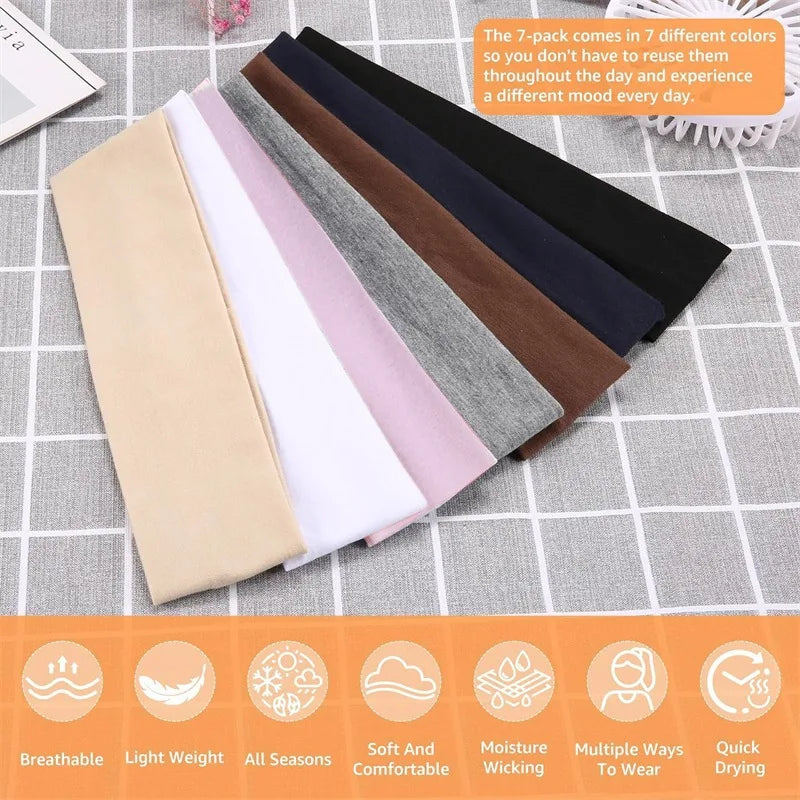 A set of seven solid elastic hair bands in various colors laid out on a gray surface.