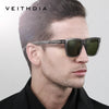 A man models classic square polarized sunglasses with dark green lenses against a light gray background.