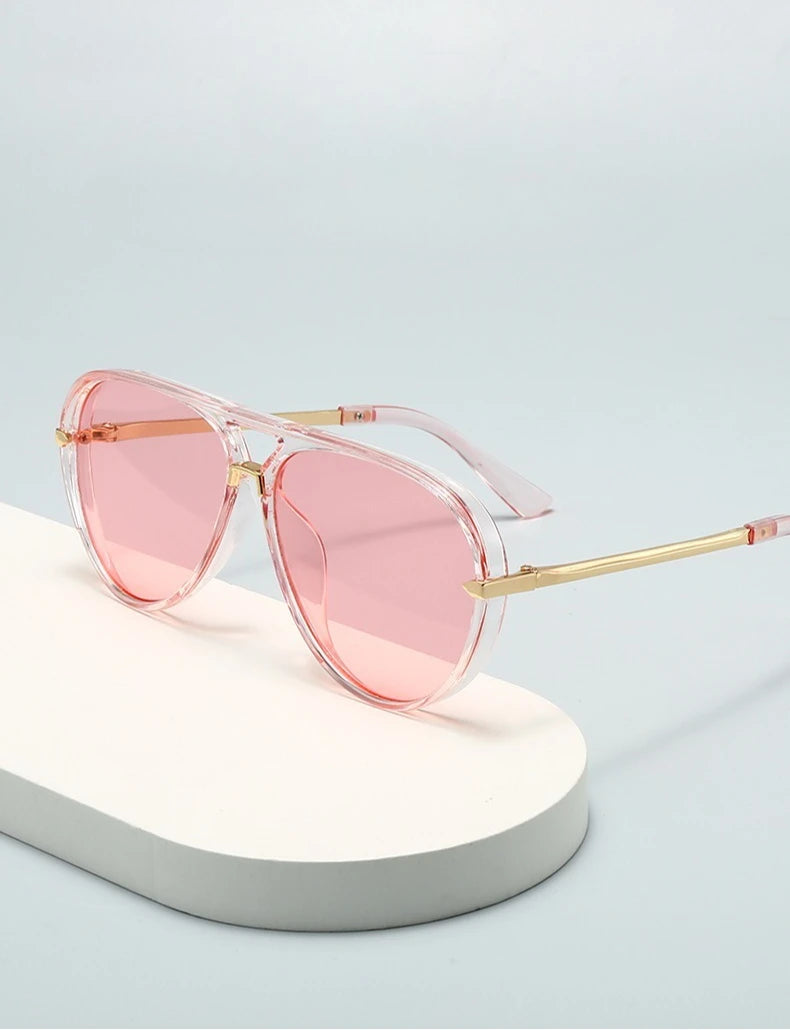 Pink tinted fashion protective sunglasses resting on a white surface.