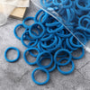 A pile of blue elastic hair bands and a clear plastic tube are shown on a gray surface.