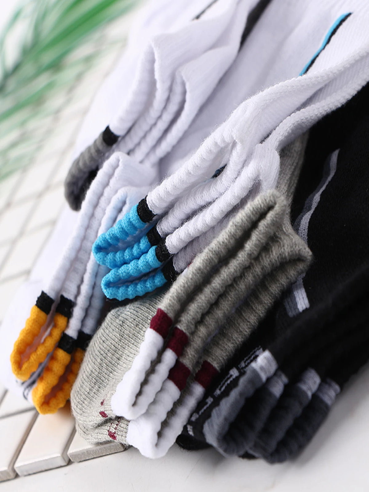 A close-up of men's color-block mesh ankle socks in various shades of gray, white, black, and blue.