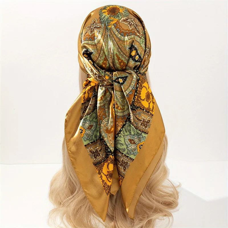 Elegant satin square scarf in gold and olive print tied around a blonde wig
