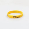 A yellow silicone wristband with the number 23 printed on it.