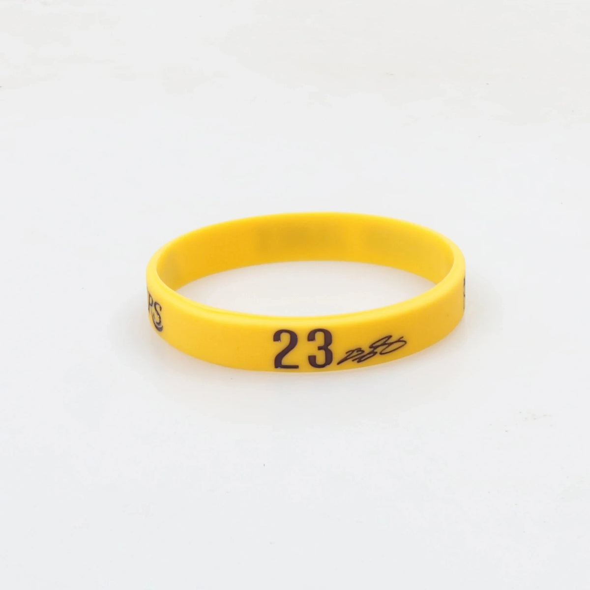 A yellow silicone wristband with the number 23 printed on it.