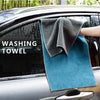 A dark gray washing towel is placed on the glass of a car, demonstrating a microfiber car cleaning towel.