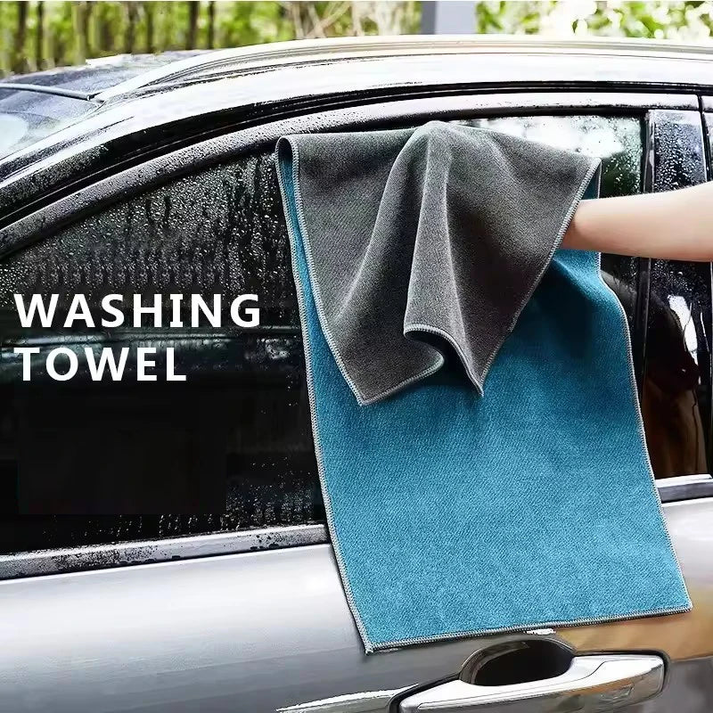 A dark gray washing towel is placed on the glass of a car, demonstrating a microfiber car cleaning towel.