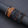 A stack of vintage beaded leather bracelets in various shades of brown and black resting on a dark surface.