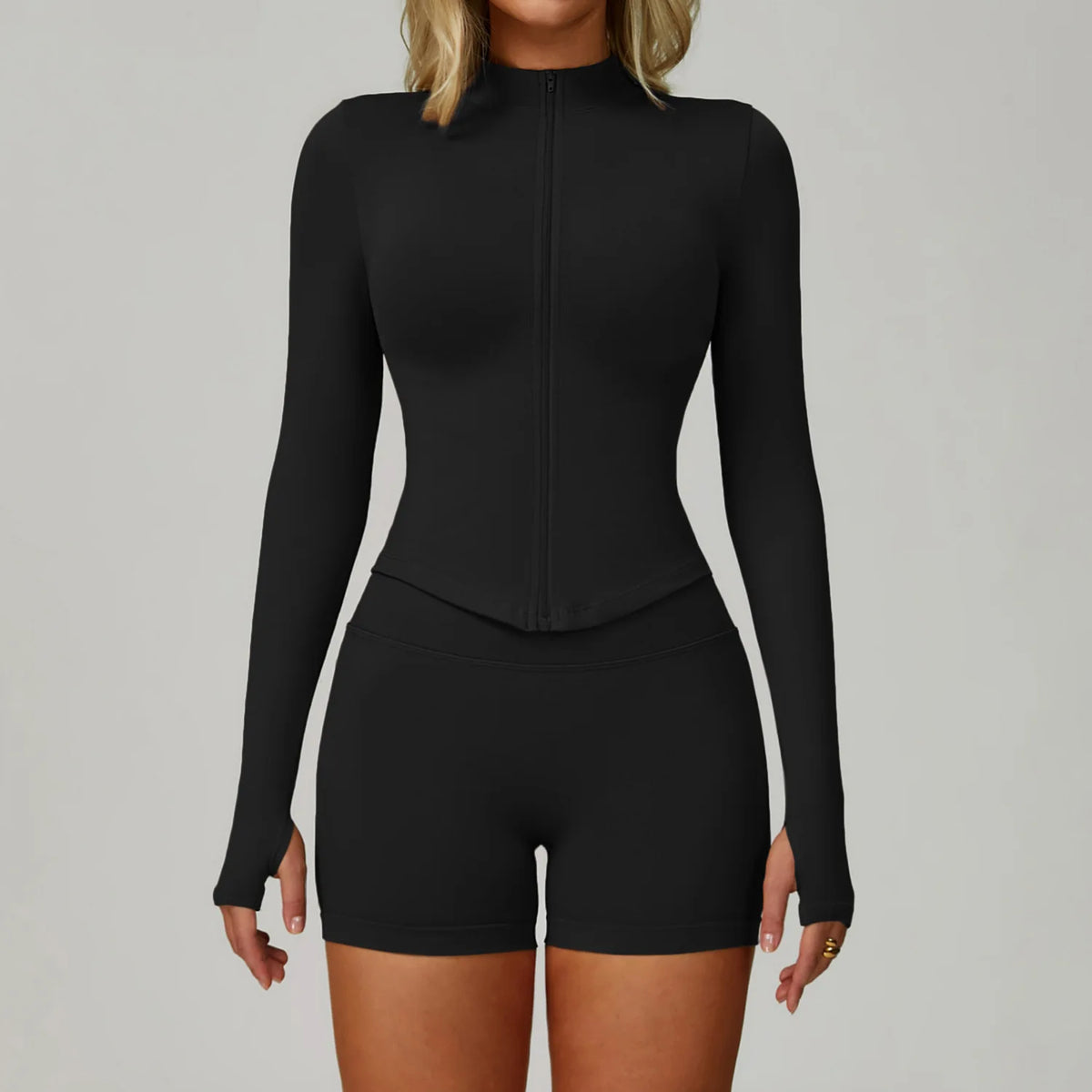 Eine Frau trägt ein schwarzes, nahtloses Sport-Yoga-Set mit langärmeligem Oberteil und Shorts.