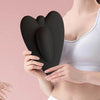 A woman holds a black pelvic floor muscle trainer against her torso.
