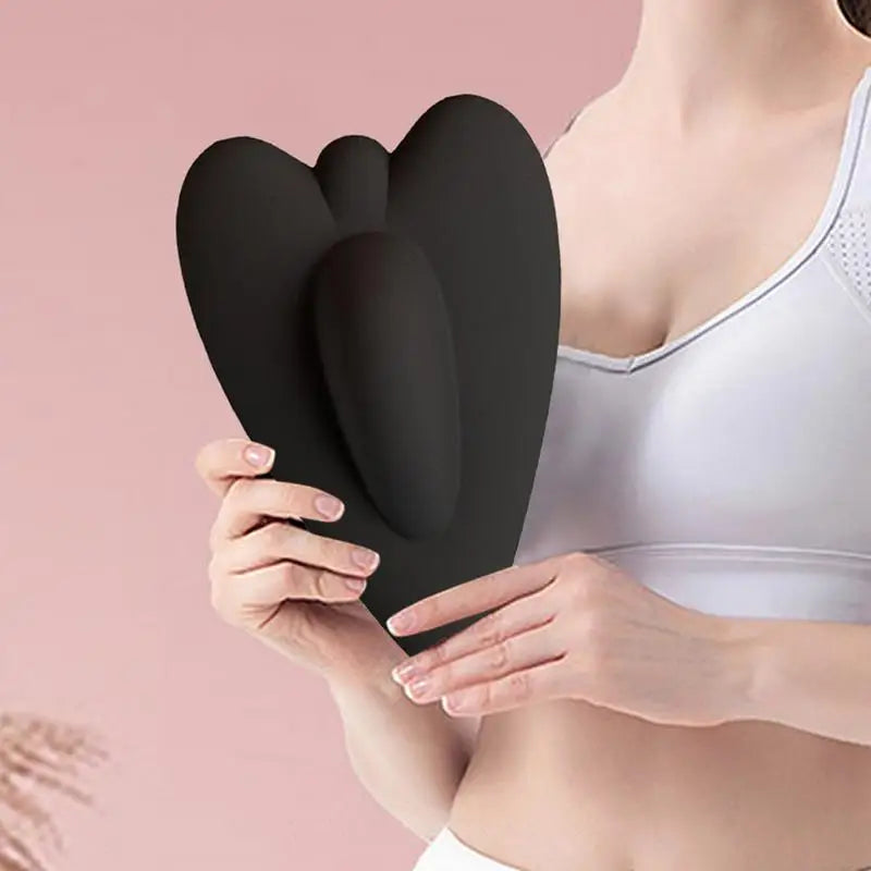 A woman holds a black pelvic floor muscle trainer against her torso.