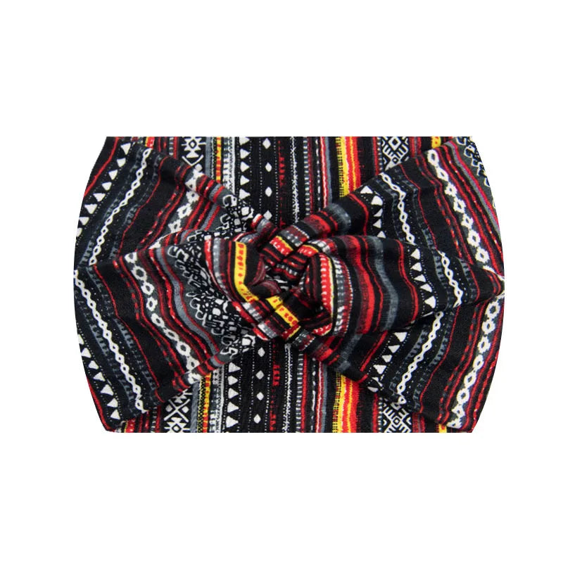 A close-up of a boho printed wide knitted headband featuring black, red, and yellow geometric patterns.
