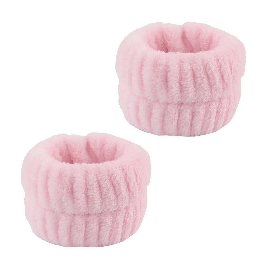 A pair of pink microfiber spa headband and wristband set with a ribbed texture.